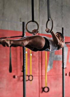 a man hanging upside down on rings in a gym