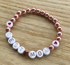 Hello and welcome. Mother's Day bracelets. You can build your own from Bead sample picture or choose one of my displays. I offer wooden beads, silver, gold, rose gold, dark gold and brownish gold beads. Also light pink pearl beads. As accents I offer heart shape beads in silver and rose gold. Start is gold, rose and silver. Round heart beads in red, blue, pink and black. Letter choice is white/black or white/rose gold. Each bracelet is stretchy and will come in an organza bag ready for gift givi Mother Day Bracelet Ideas, Mom Bead Bracelets, Mothers Day Bracelet Ideas, Mother’s Day Bracelet Ideas, Mothers Day Bracelets Diy, Handmade Rose Gold Bracelets For Mother's Day, Personalized Name Bracelet For Best Friend, Mother's Day Gift, Customized Bracelets For Best Friend Gift On Mother's Day, Personalized Name Bracelet For Best Friend And Mother's Day