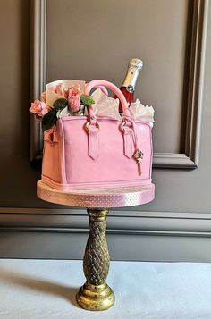 a pink purse cake sitting on top of a gold plated stand next to a mirror