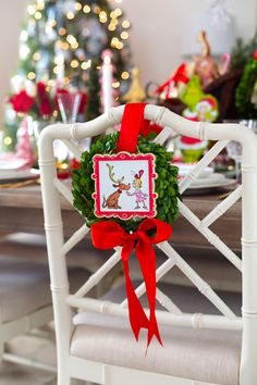 a white chair with a red ribbon around it and a christmas wreath on the back