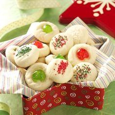 small christmas cookies in a red and white box on a green tablecloth next to other holiday decorations