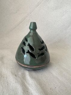 a green vase sitting on top of a white cloth