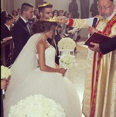 a bride and groom are getting married at the alter with other people in the background