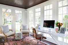 a home office with two chairs and a computer on a desk in front of large windows