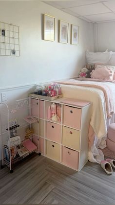 a bedroom with white walls and pink storage boxes on the floor next to a bed