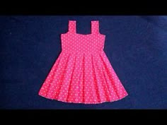 a pink and white polka dot dress sitting on top of a blue surface