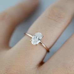 a woman's hand with a diamond ring on her left hand and the other hand holding an engagement ring