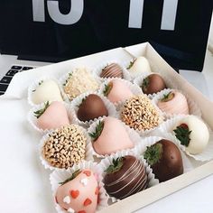 a box filled with chocolate covered strawberries on top of a white table next to a laptop