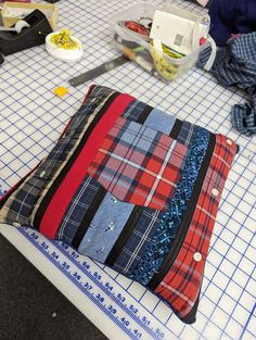 a quilted bag sitting on top of a table next to scissors and other sewing supplies