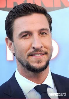 a close up of a person wearing a suit and tie with a beard smiling at the camera