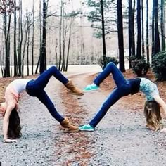 two girls doing handstands in the middle of a dirt road surrounded by trees