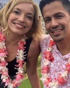 a man and woman are posing for a photo with leis around their necks in the grass