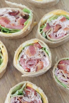 several sandwiches with meat, cheese and lettuce are arranged on a wooden surface