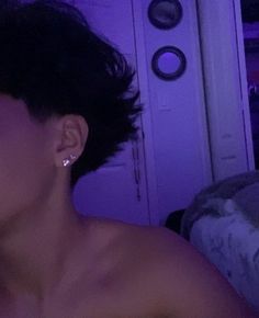 a woman with no shirt on in front of a purple light and wearing ear rings