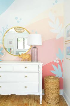 a white dresser sitting next to a mirror on top of a wooden floor in a room