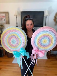 a woman holding two large lollipops on top of each other in front of a tv