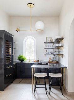 a kitchen with black cabinets and gold accents