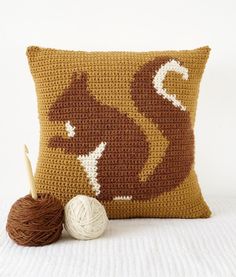 a crocheted pillow with a ball of yarn next to it