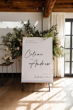 a sign that is sitting in the middle of a room with flowers and greenery