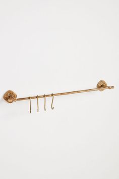 a pair of gold hooks hang on a white wall