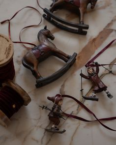 four toy figurines are sitting on a marble surface with thread spools