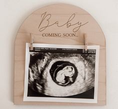 a wooden sign that says baby coming soon hanging on a wall next to a photo