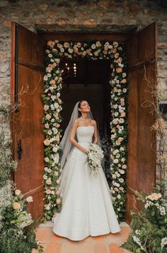 a woman standing in front of a doorway wearing a wedding dress