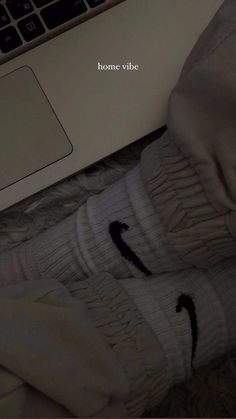 someone's feet in white socks with the word home vibe written on them next to a laptop