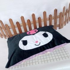 a black and white pillow sitting on top of a wooden bench next to a fence