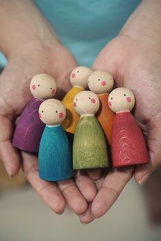 a person holding small wooden dolls in their hands