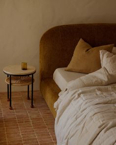 a bed sitting next to a small table on top of a floor near a wall