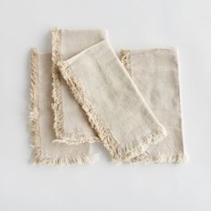 three pieces of white linen with fringes on them