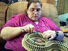 a woman sitting in a chair working on some bead bracelets with her hands