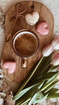 a cup of coffee with marshmallows and heart shaped cookies next to it