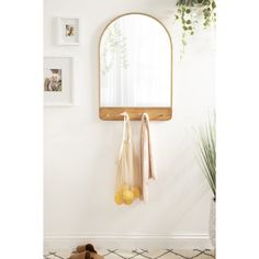 a mirror hanging on the wall next to a pair of shoes and a plant in a vase