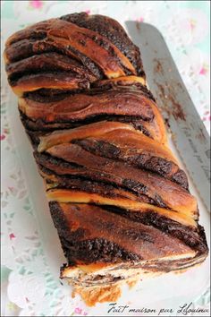 a loaf of chocolate bread sitting on top of a white paper covered table next to a knife