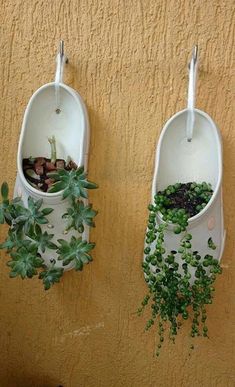 two white hanging planters with plants in them