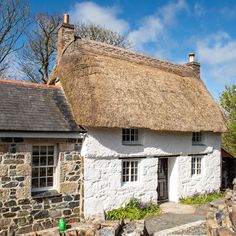 an old thatched roof house with stone walls