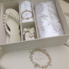 an open shoe box with two pairs of white shoes and one pair of slippers