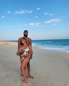 a man and woman are standing on the beach