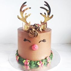 the cake is decorated with deer antlers on it's head and has pink frosting