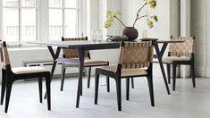 a dining room table with chairs and a vase on top of it in front of a window