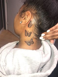 a woman is getting her hair done with butterflies on her neck and behind her head