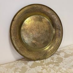 a gold plate sitting on top of a table next to a white and beige wall