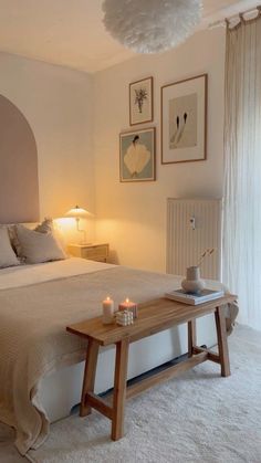 a bedroom with a large bed and pictures on the wall above it, along with candles