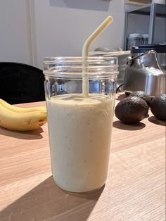 a glass with a straw in it sitting on a table next to bananas and other items