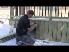 a man is painting the side of a wooden fence with a paint bottle and brush