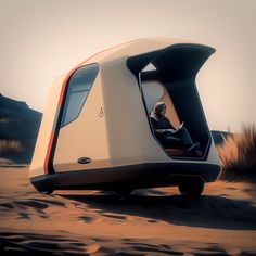 a man sitting in the driver's seat of a futuristic vehicle on sand dunes