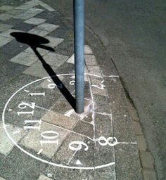 a clock on the sidewalk has been drawn with chalk