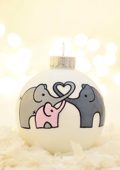 an ornament with two elephants and a heart in the middle on top of shredded paper